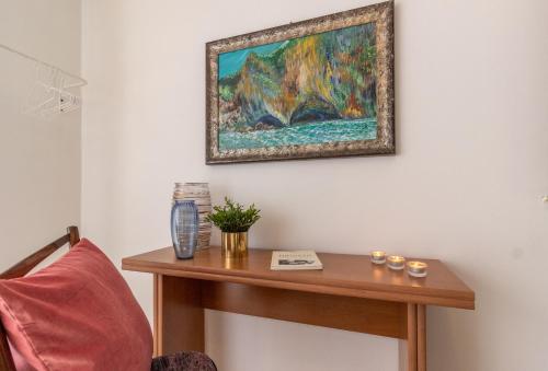 a painting hanging on a wall above a wooden table at Scariceddu in Riposto