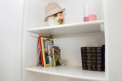 een boekenplank met boeken en een hoed erop bij Lo studio di Nonno in Noci