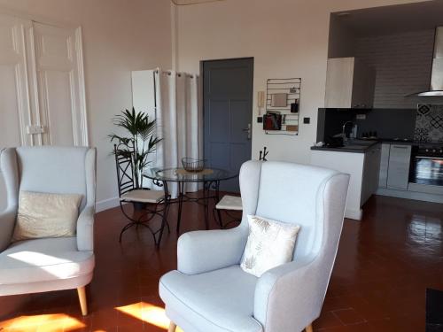 een woonkamer met 2 stoelen en een tafel bij Appartement avec balcon, bord du canal, Wifi. in Narbonne