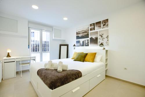 Habitación blanca con cama grande y escritorio. en Charming Madrid La Elipa - 3 dormitorios, en Madrid