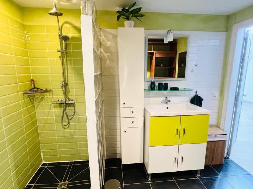 a yellow bathroom with a sink and a shower at Maisonnette indépendante au calme in Vittel