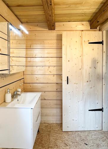 La salle de bains est pourvue d'un lavabo blanc et d'un mur en bois. dans l'établissement Escale au cœur de l'Alsace, à Wolfisheim