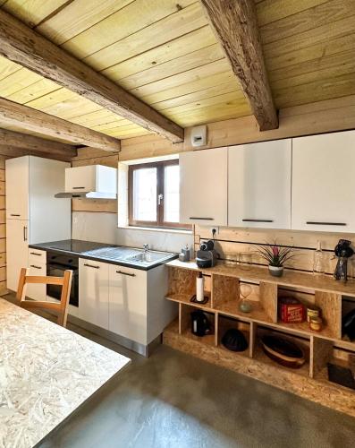 une cuisine avec des armoires blanches et un plafond en bois dans l'établissement Escale au cœur de l'Alsace, à Wolfisheim