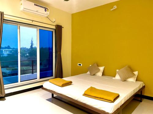 Un dormitorio con una cama con paredes amarillas y una ventana en Scarlet Resort Alibag en Alibaug