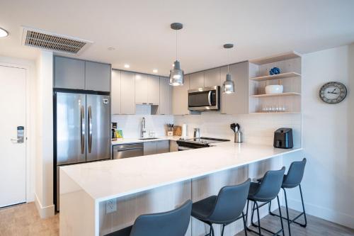 a kitchen with a counter with chairs and a refrigerator at Alpine Dream by Revelstoke Vacations in Revelstoke
