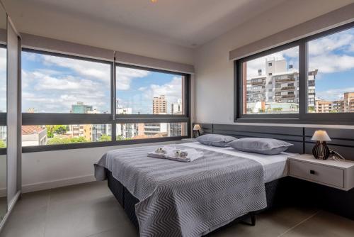 um quarto com uma cama e janelas grandes em LIV - Apartamento 907 em Porto Alegre