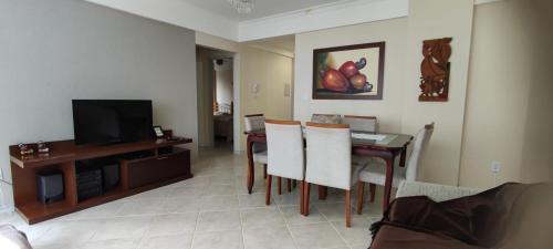 a living room with a dining room table and a television at Apartamento Balneário Camboriu in Balneário Camboriú