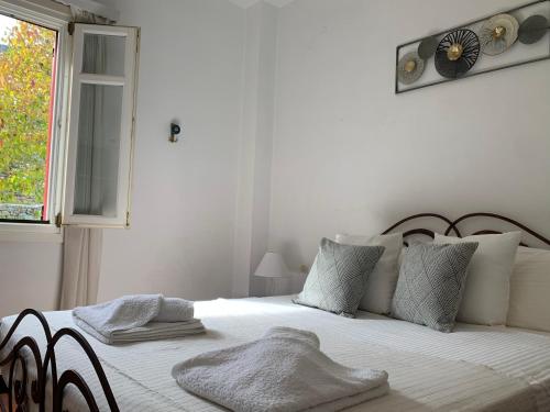 1 dormitorio blanco con 1 cama con reloj en la pared en Pandora Villa en Ítaca