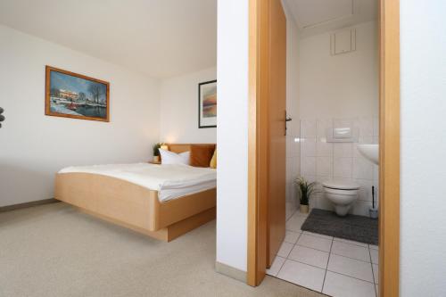 ein Schlafzimmer mit einem Bett und ein Badezimmer mit einem WC in der Unterkunft Ferienzimmeranlage Deutsches Haus Deutsches Haus App 35 in Wustrow