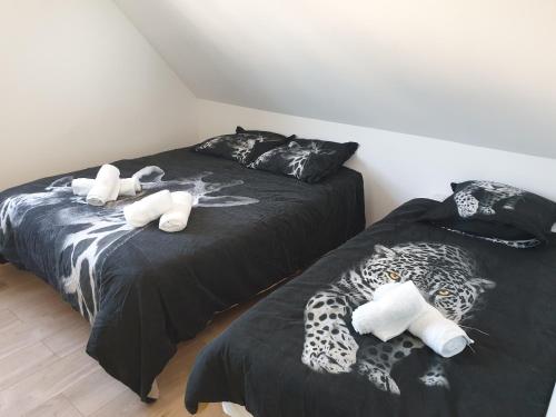 twee bedden in een kamer met zwart-witte lakens bij Le Safari - Dormir Comme A La Maison in Guérande