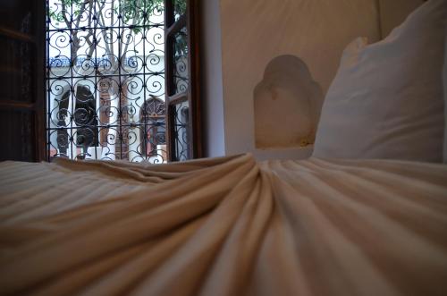 a bed with white sheets and a window with a curtain at Riad Maialou & SPA in Marrakech
