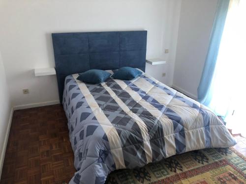 Bett mit blauem Kopfteil in einem Schlafzimmer in der Unterkunft Apartamento Rio Minho in Vila Nova de Cerveira