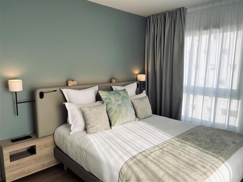 a bedroom with a large bed with pillows and a window at Residhome Quai d’Ivry in Ivry-sur-Seine