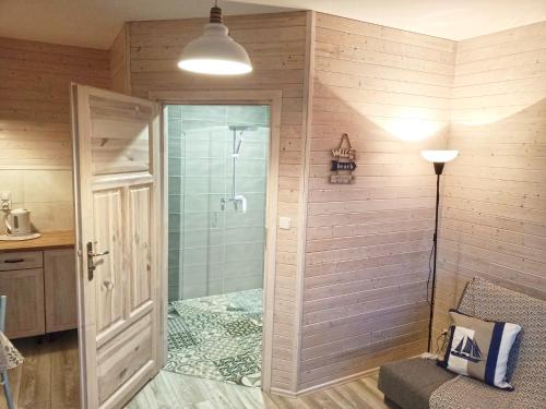 La salle de bains est pourvue d'une douche avec une porte en verre. dans l'établissement Rybacki Domek 50 metrów do morza!, à Dziwnów