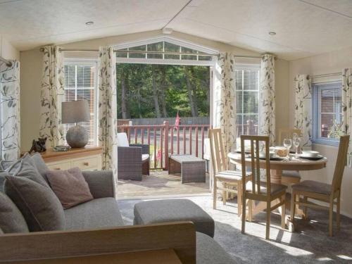 een woonkamer met een bank en een tafel bij Poppy Lodge Glendevon Scotland in Glendevon