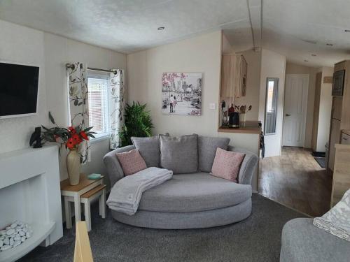 ein Wohnzimmer mit einem grauen Sofa und einer Küche in der Unterkunft Poppy Lodge Glendevon Scotland in Glendevon
