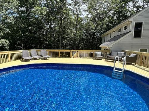 a large blue swimming pool with chairs and a fence at AMAZING Home with PRIVATE HEATED POOL, GAME ROOM & FIRE PIT! in East Stroudsburg