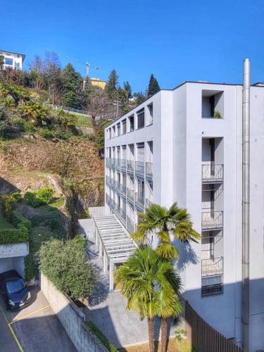 a white building with a palm tree in front of it at Bilocale con terrazzi Via Antonio Riva 3 by LR in Lugano