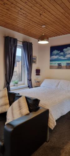 a bedroom with a bed and a couch and a window at Faodail, 1 Bed Studio apartment at Ravenscraig Castle and Park in Fife