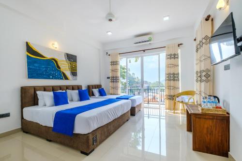 two beds in a room with a television and a balcony at Queens mount Ridge in Kandy