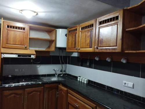 une cuisine avec des placards en bois et des comptoirs noirs dans l'établissement N20 Residence vitel pour famille, à Ifrane