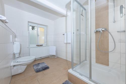 a white bathroom with a shower and a toilet at Gasthaus Hinterbrühl in Salzburg