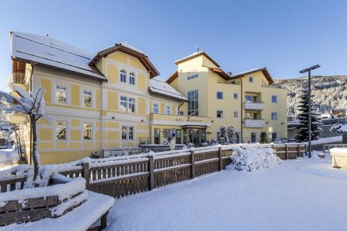 a large yellow building with a fence in the snow at Hotel Kronplatz in Valdaora