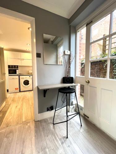 a kitchen with a table and a stool in front of a door at Chester's - Central Chester Stays - City Walls - Private Garden Overlooking River Dee in Chester