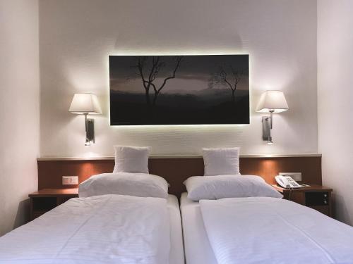 two beds in a hotel room with a painting on the wall at Faulenzerhotel in Friedersbach