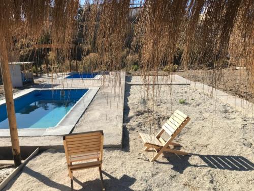 two chairs sitting in the sand next to a swimming pool at Eco Lodge Loro Tuerto in Guanaqueros