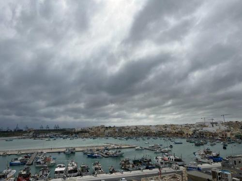 Ein Haufen Boote in einem Hafen an einem wolkigen Tag in der Unterkunft Marsaxlokk SeaView 2 Bedroom Penthouse in Marsaxlokk