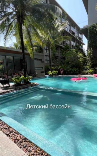 a swimming pool with a palm tree and a building at Diamond Apartments Phuket Bangtao in Phuket Town