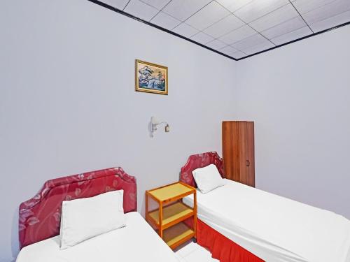 um quarto com duas camas e uma mesa em OYO 92337 Wisma Arwini Syariah em Sinjay