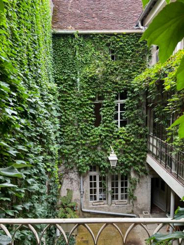 un edificio cubierto de hiedra con ventanas y balcón en La Verrière - Chambre d'hôtes et gîte de charme en Poligny
