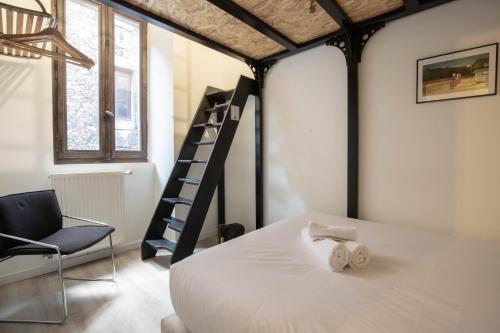 a bedroom with a bed and a chair and a ladder at Beethoven Super emplacement vieille ville in Annecy