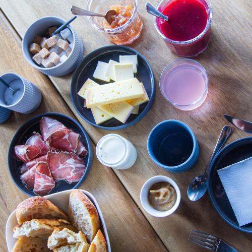 Una mesa de madera cubierta con platos de queso y pan. en Maison Cimes, en Les Orres
