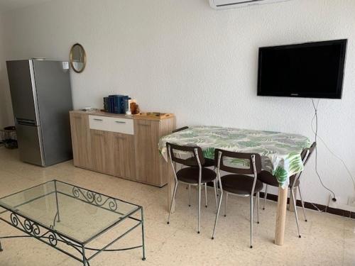un salon avec une table, des chaises et une télévision dans l'établissement Appartement ⭐⭐ à Balaruc-les-Bains avec climatisation et jardin, animaux admis - FR-1-503-156, à Balaruc-les-Bains