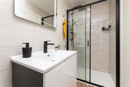 a white bathroom with a sink and a shower at Apartments Neptun in Baška
