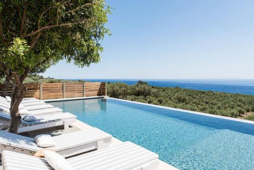a swimming pool with lounge chairs and the ocean at Villa Olvía in Sfakia