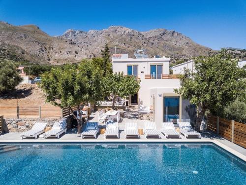 a swimming pool with chairs and a villa at Villa Olvía in Sfakia