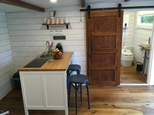 a kitchen with a sink and a counter with stools at Gemütliches Tinyhouse im Garten einer Villa in Bad Sauerbrunn