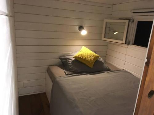 a small room with a bed with a yellow pillow at Gemütliches Tinyhouse im Garten einer Villa in Bad Sauerbrunn