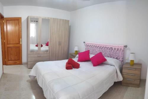 ein Schlafzimmer mit einem großen weißen Bett mit roten Kissen in der Unterkunft Casa La Orilla 1 in Playa Honda