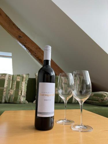 a bottle of wine sitting on a table with two wine glasses at Penzion Viktoria in Znojmo