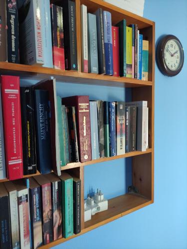 a book shelf filled with books next to a clock at Pension Niki in Skála Sykaminéas