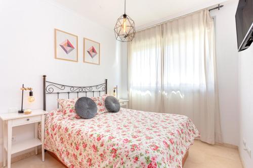 - une chambre dotée d'un lit avec un couvre-lit floral dans l'établissement Araucaria Garden & Parking, à Malaga