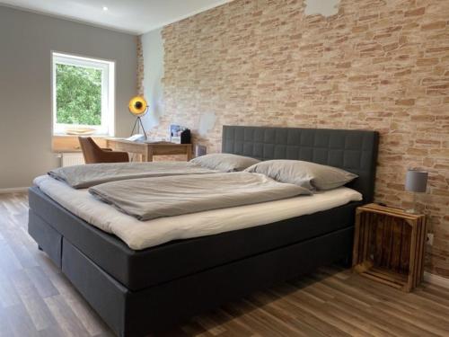 1 cama grande en un dormitorio con pared de ladrillo en FeWo Diekshörn an der Nordsee Elbe am Nord-Ostsee-Kanal, en Ramhusen