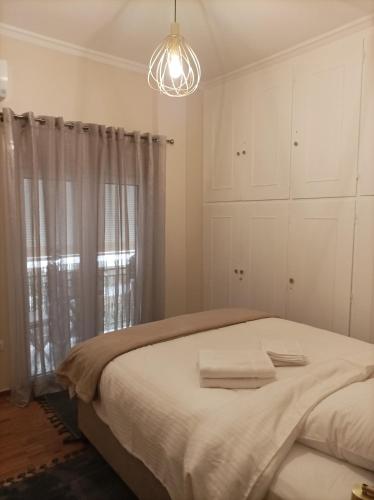 biała sypialnia z łóżkiem i żyrandolem w obiekcie Calypso w Atenach