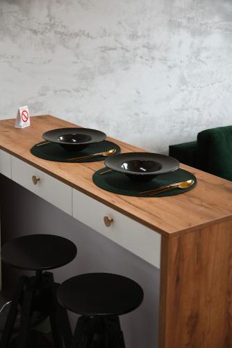 a wooden table with two black plates and stools at CROWN apartment in Subotica