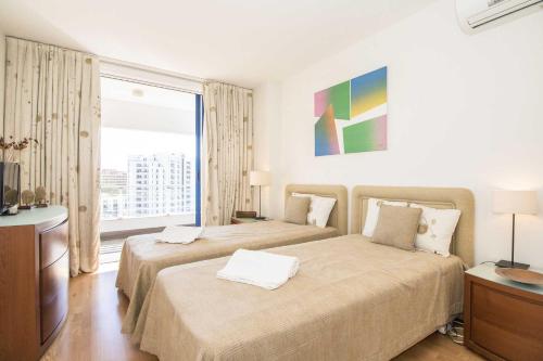une chambre d'hôtel avec deux lits et une grande fenêtre dans l'établissement Apartamento Valerie, à Vilamoura